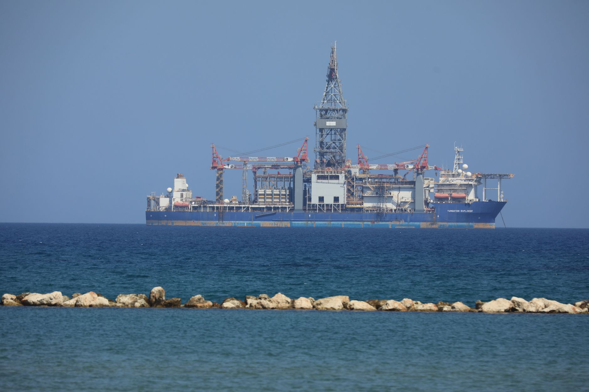 Plateforme de forage offshore flottant sur une mer calme avec un ciel bleu clair en arrière-plan.
