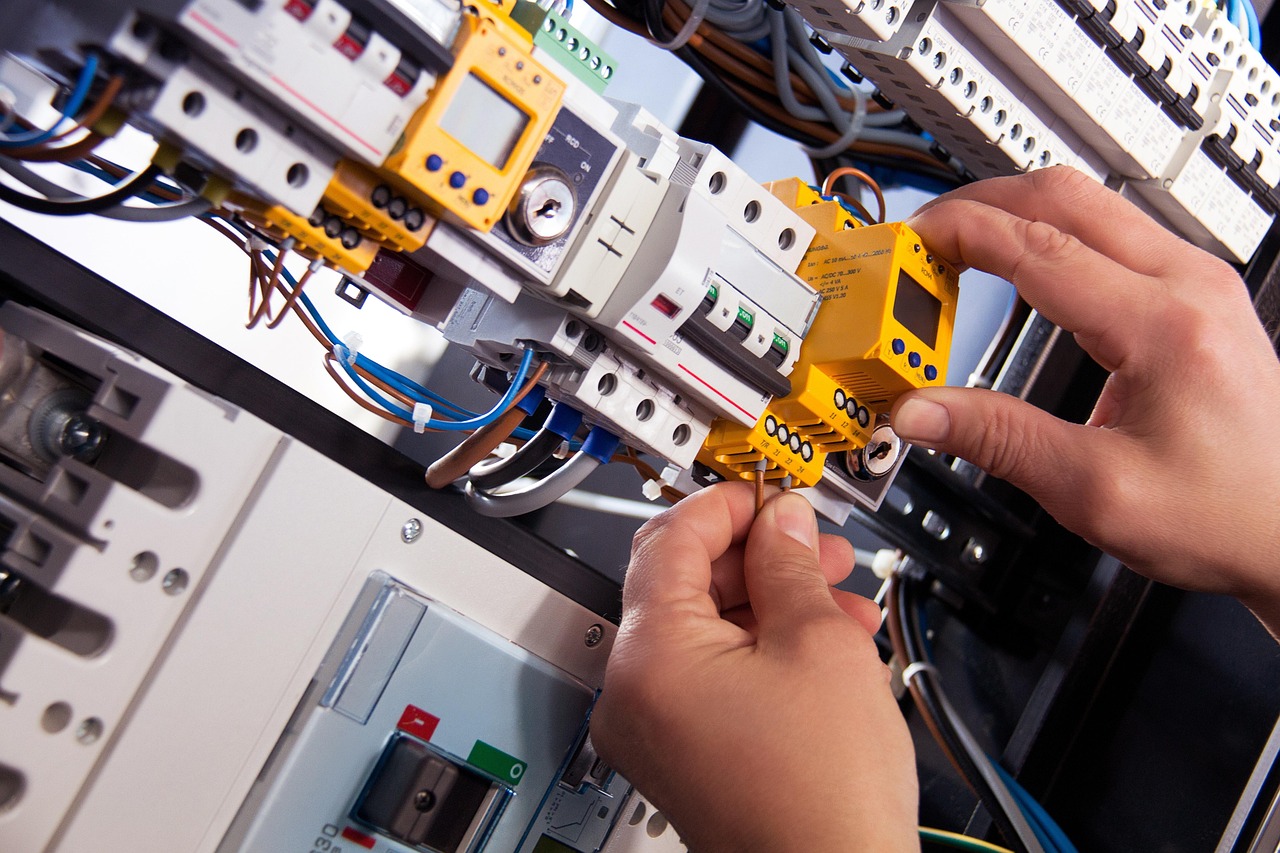 Mains qui raccordent des disjoncteurs dans un tableau électrique, exercice type d'une formation en électricité du bâtiment